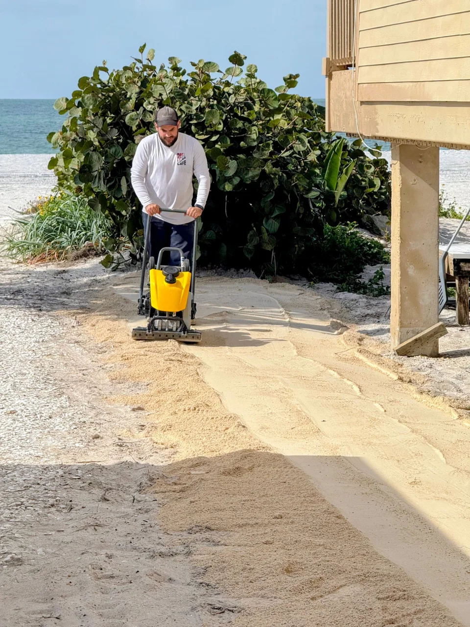 Professional plate compactor packing limestone base for shell path Florida